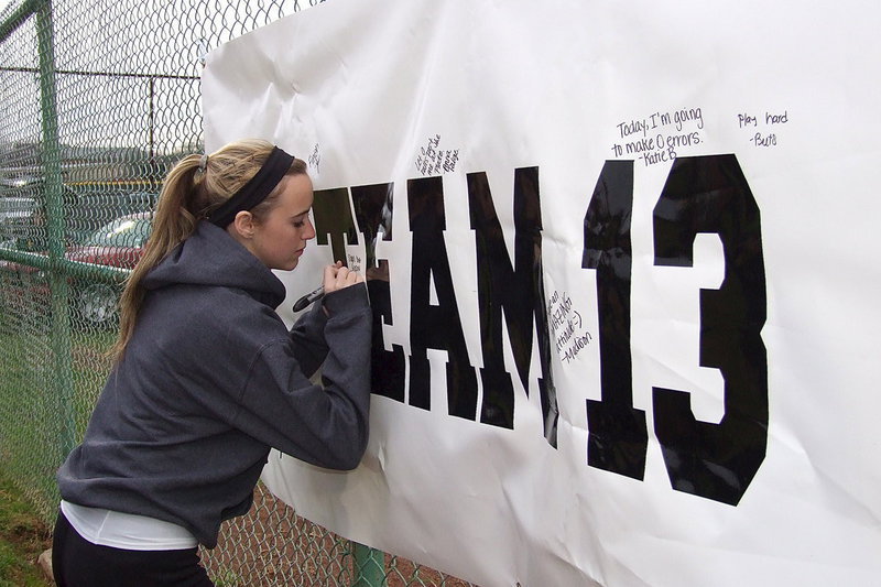 Image: Kelsey Nelson signs the sign listing her goal for the upcoming game.