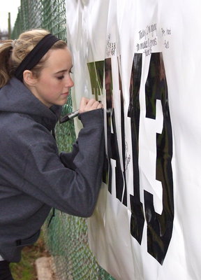 Image: Sophomore Kelsey Nelson adds her game goal to the Team 13 banner before the game against Hubbard.