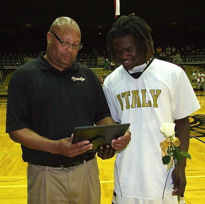 Image: Escorting senior Gladiator Ryheem Walker is assistant coach Larry Mayberry, Sr. as they both enjoy the personalized picture collage presented to all the seniors during Italy’s Senior Night.
