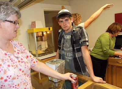 Image: Justin Wood helps the junior class earn money by working the concession stand during senior night. Here, Justin serves DeeDee Hamilton a soda as classmate Shad Newman directs traffic.