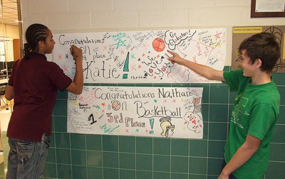 Image: Devonteh Williams and Dylan McCasland, as well as many other Italy HS students and teachers, sign their congratulations on the banners hanging outside the classroom to welcome special athletes Katie Connor and Nathan Brock back from their olympic games.