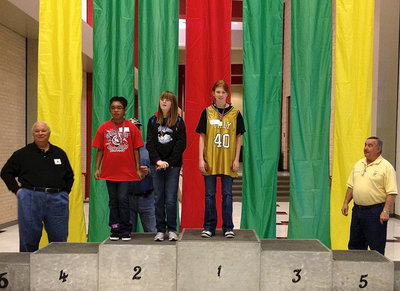 Image: Italy Lady Gladiator #40 Katie Connor graciously accepts her 1st place gold medal as she towers high above on the podium.