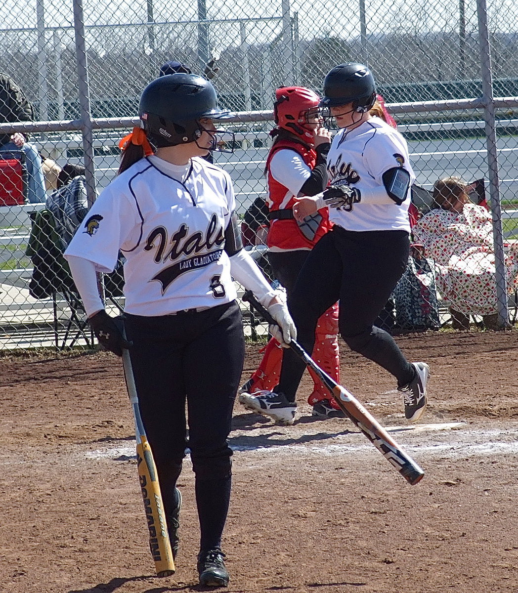 Image: Benefiting a Kelsey Nelson hit, Morgan Cockerham and Katie Byers cross home plate for Italy.