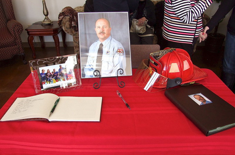 Image: A family photo, a register book and a picture of Lieutenant Greg Pickard, 54, a fallen Bryan, Texas firefighter and a former Gladiator graduate of Italy High School, impacts guests as they enter a hometown visitation held on Saturday, March 2 inside the Italy Boze Community Center to honor a hero.