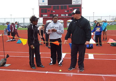Image: Assisting Kortnei Johnson in the long jump are coaches Jessika Robinson and Hank Hollywood.
