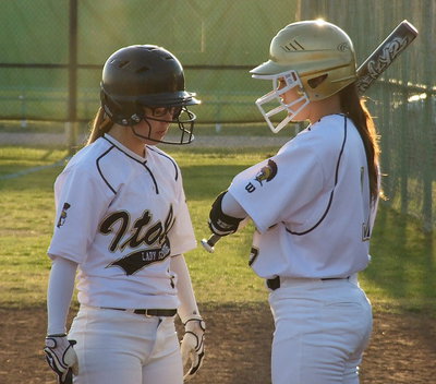 Image: Bailey Eubank and Lillie Perry go over the play calls before taking their turns at bat.