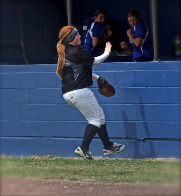 Image: Chasing a foul ball, first baseman Katie Byers(13) makes contact with the dugout wall.