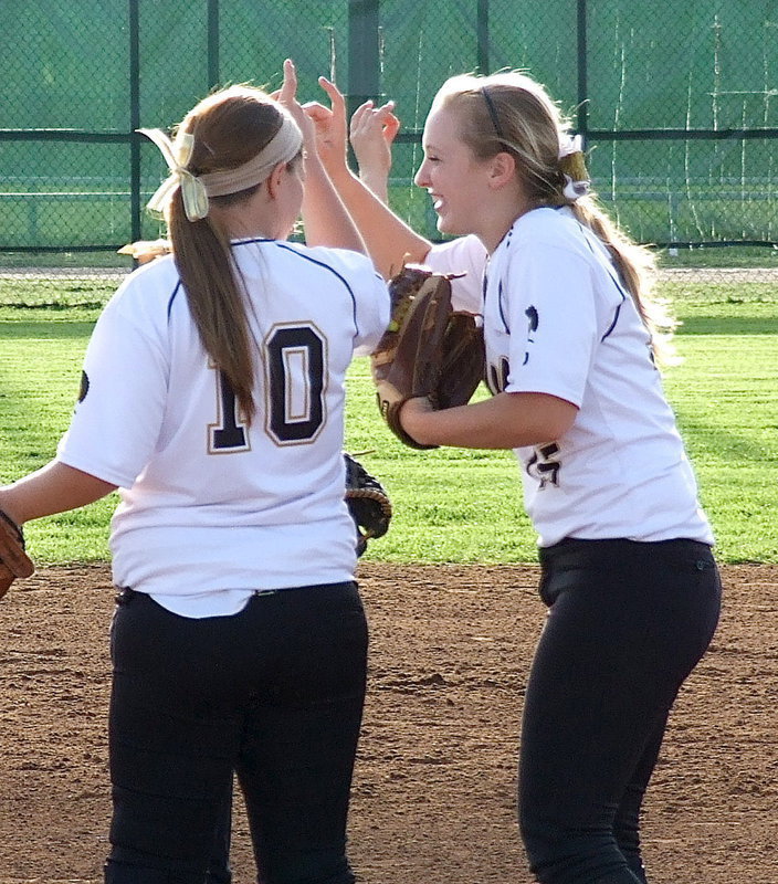 Image: Pitcher Jaclynn Lewis(15) shares a light moment with Paige Westbrook(10) and the rest of the infielders before going back to work.