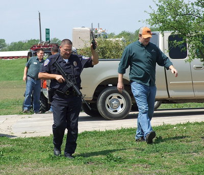 Image: Milford Police Chief Carlos Phoenix is escorted around the Monolithic campus with a man hunt underway after a traffic stop along Highway 35.