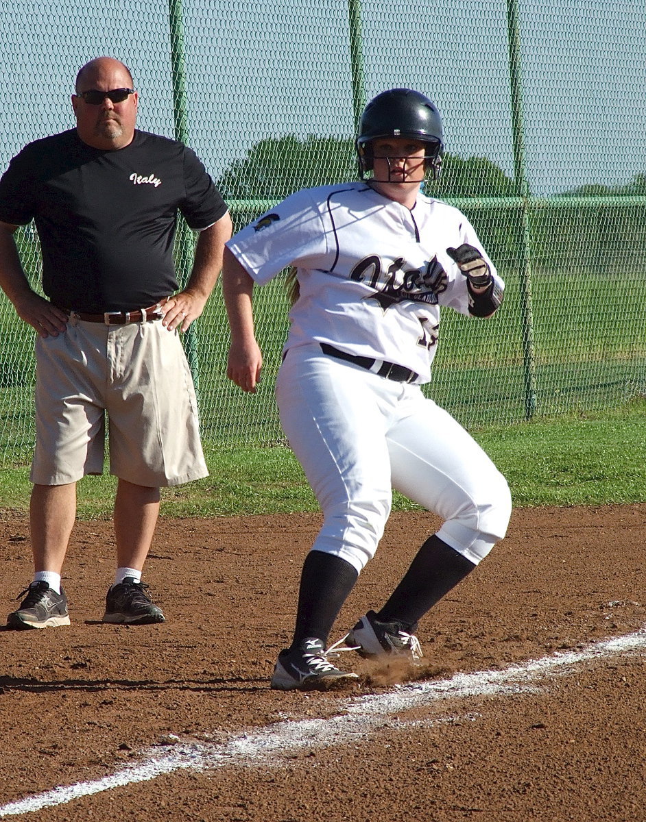 Image: Lady Gladiator senior Katie Byers(13) stirs up the third base line while looking for a chance to reach home plate while head coach Wayne Rowe observes the action.