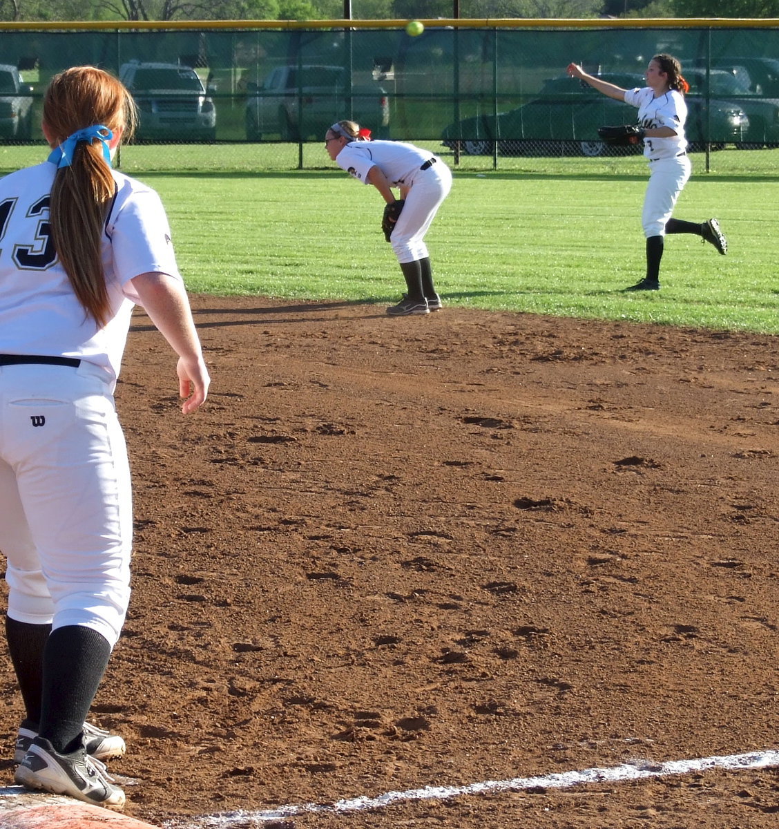 Image: Senior first baseman Katie Byers(13) looks on as teammate and senior outfielder Morgan Cockerham(8) covers a grounder and then throws to second base over Bailey Eubank(1) who ducks down to make way for, “Mo.”