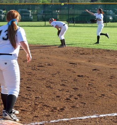 Image: Senior first baseman Katie Byers(13) looks on as teammate and senior outfielder Morgan Cockerham(8) covers a grounder and then throws to second base over Bailey Eubank(1) who ducks down to make way for, “Mo.”