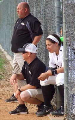 Image: Starting senior catcher Alyssa Richards(9) uses a bucket to get as close as she can to sophomore backup catcher Madison Washington in order to lend advice while head coach Wayne Rowe (standing) and assistant coach Michael Chambers instruct the other eight Lady Gladiators.
