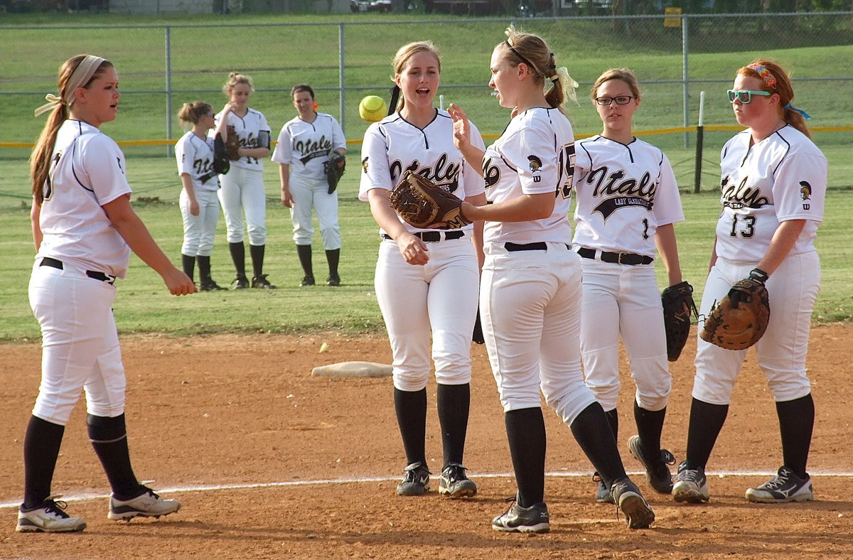 Image: Lady Gladiator outfielders Tara Wallis(5), Kelsey Nelson(14) and Morgan Cockerham(8) get ready to wrap up their undefeated district championship against Waxahachie Faith Family as infielders Paige Westbrook(10), Madison Washington(2), Jaclynn Lewis(15), Bailey Eubank(1) and Katie Byers(13) play hot potato to get things started.