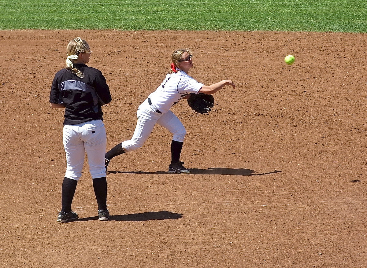 Image: Pitcher Jaclynn Leiws(15) stays clear as second baseman Bailey Eubank(1) covers a grounder and then throws to Katie Byers at first base for the out.