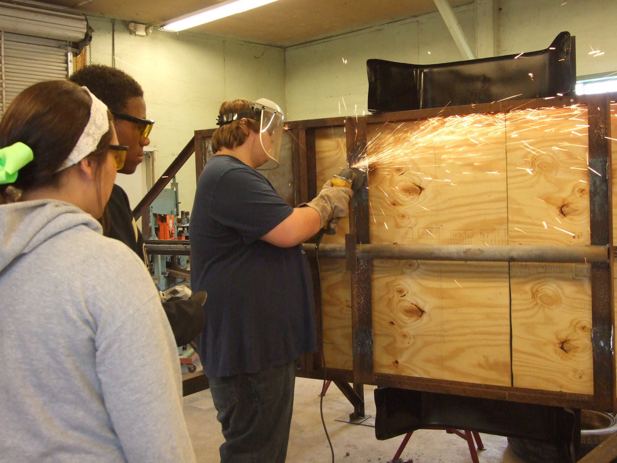 Image: Logan Owen grinds the axle of the new dog trailer.