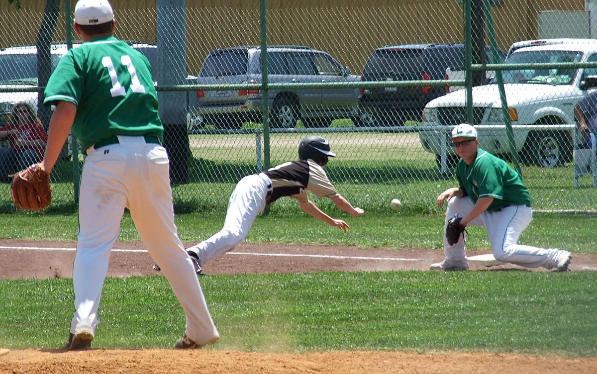 Image: Italy’s Clayton Miller(8) lunges back to first base just in time.