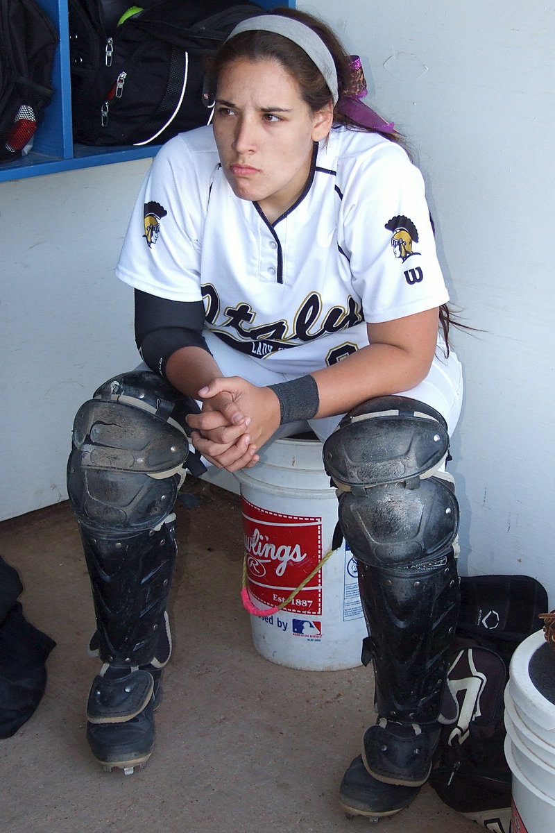 Image: Catcher Alyssa Richards(9) conserves her energy while listening intently to the advice her mom and coach, Tina Richards, offers her.