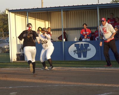Image: Pitcher Jaclynn Lewis(15) turns in a hustle play by running down a ground ball and then throwing on the run, and on target, to first baseman Katie Byers(13) who makes the catch for an out.