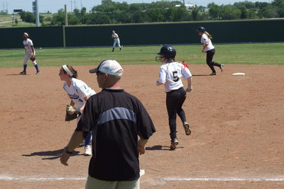 Image: First base coach Michael Chambers tries to get Paige Westbrook(10) on second and Tara wallis(5) on first to advance around the bases.