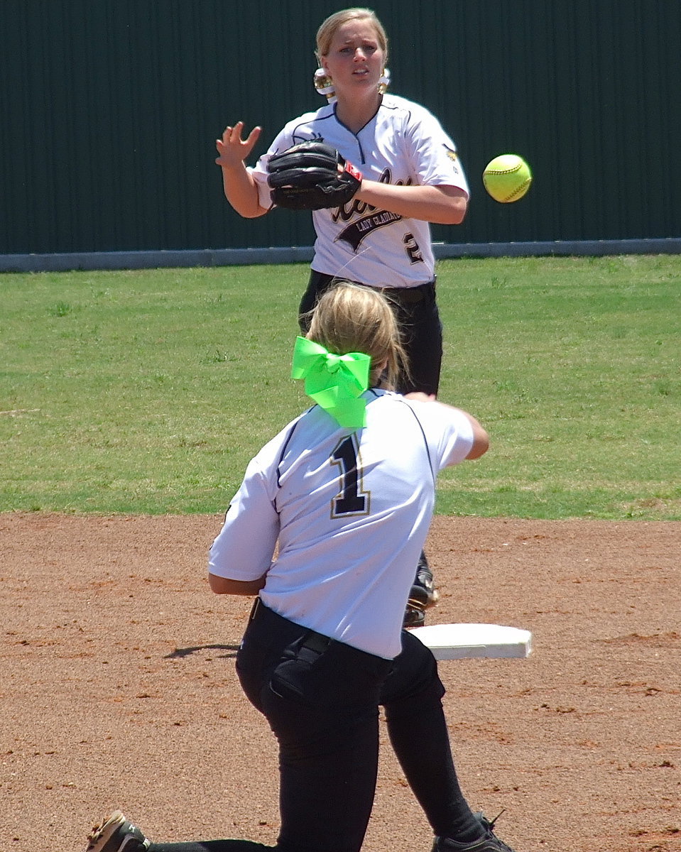 Image: Second baseman Bailey Eubank(1) practices turning two with shortstop Madison Washington(2) during warmups.