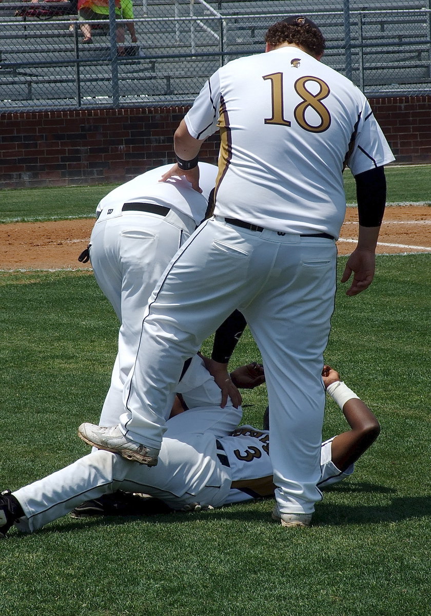 Image: Kevin Roldan(16) and John Byers(18) stretch out teammate Marvin Cox(3).