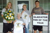 Image: Lady Gladiator, Jaclynn Lewis, and Gladiator, Zain Byers, present, Alice Riddle, and her daughter, Joy Moneyhon, with a bouquet of flowers, Gladiator Fan of the Year T-Shirts and a Gladiator Fan of the Year yard sign. The gifts are in appreciation for the mother-daughter team’s efforts in supporting the Italy Athletic program.