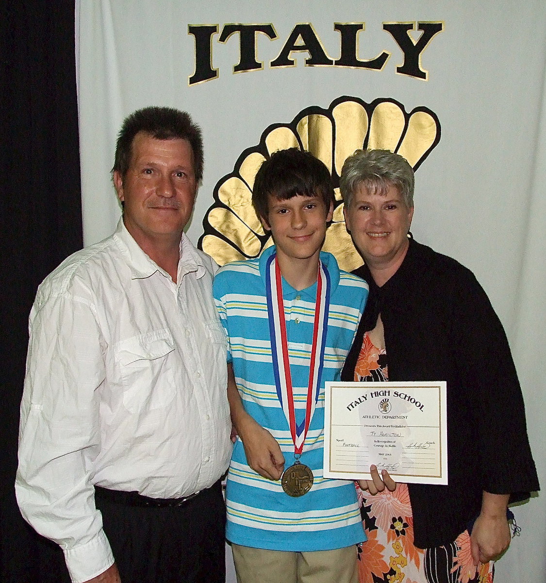 Image: Pictured with parents, Lee and DeeDee Hamilton, team manager, Ty Hamilton, displays his State semifinal medal and certificate of achievement.