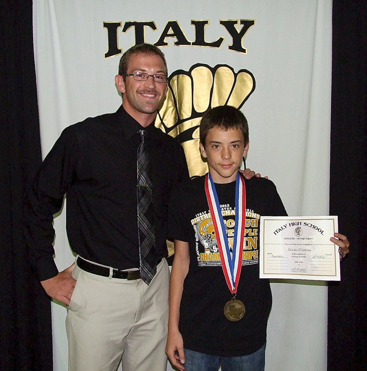 Image: Accompanied by this season’s Offensive Coordinator, Nate Skelton, is team manager, Dylan McCasland, who displays his State semifinal medal and certificate of achievement.