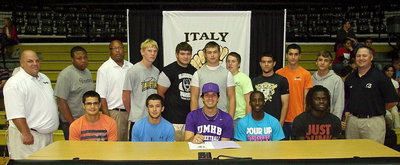 Image: During his signing party to the University of Mary Hardin-Baylor, Cole Hopkins is joined by Italy Gladiator Basketball teammates and coaches. (Back row): Head coach Brian Coffman, Darol Mayberry, assistant coach Larry Mayberry, Sr., Cody Boyd, Kevin Roldan, Zain Byers, John Escamilla, Tyler Anderson, Mason Womack, Levi McBride and assistant coach Josh Ward. (Front row): Reid Jacinto, Caden Jacinto, Cole Hopkins, Marvin Cox and Ryheem Walker.