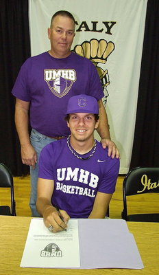 Image: Proud father Brad Hopkins supports his son, Cole Hopkins, as Cole prepares to sign his letter of intent to play basketball for the University of Mary Hardin-Baylor Crusaders.