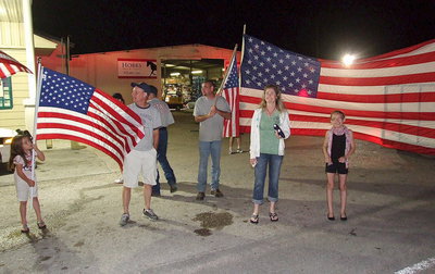 Image: Morgan Chambers, Italy Firefighters, Randy Boyd and Brad Chambers, City of Italy employee Rhonda Cockerham and Madie Chambers help form a patriotic spirit line that will lead the Birdman to his checkpoint setup in front of Hobbs Feed &amp; Supply in Italy.