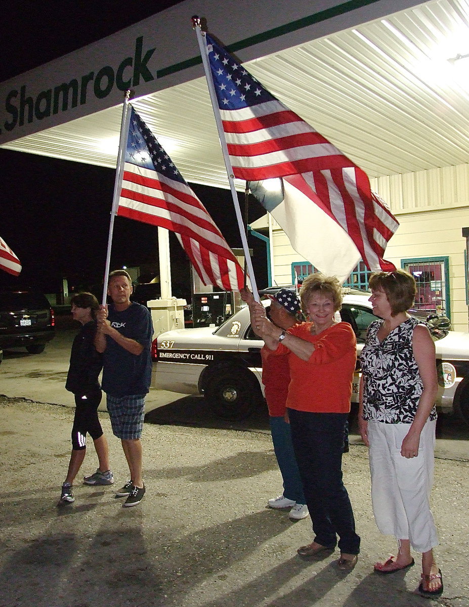 Image: Joyce Hobbs of Hobbs Feed &amp; Supply in Italy joins the spirit line with her flag held high as the Birdman approaches Italy.