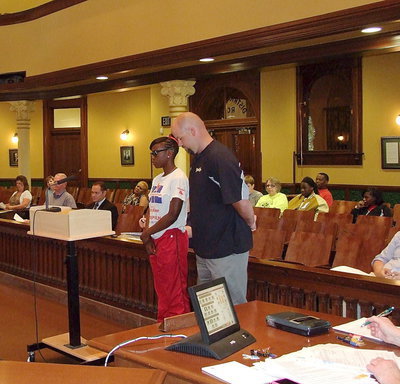 Image: Kortnei Johnson, and coach, Hank Hollywood, take in the moment as Johnson hears the words, "Now therefore be it proclaimed that the Ellis County Commissioners’ Court does hereby salute Kortnei Johnson of Italy, Texas for bringing recognition and honor to the Italy ISD, the City of Italy and Ellis County with her record-breaking wins at the 2013 State UIL 1A Track &amp; Field Meet.