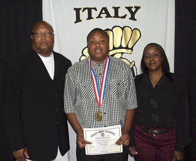 Image: Pictured with parents, Larry Mayberry, Sr. and his wife Barbara, junior Gladiator, Darol Mayberry, displays his State semifinal medal and certificate of achievement.
