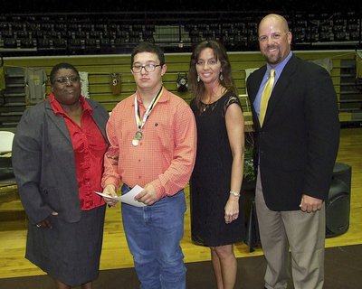 Image: CBI instructors Brenda Davis and Teresa Young, along with AD/HFC Coach Hank Hollywood, present senior CBI student Blake Vega with a certificate as he stands proud with his Special Olympic medals around his neck.