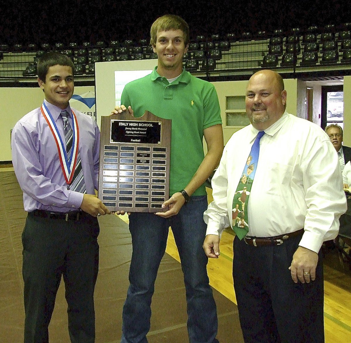 Image: Assistant coach, Wayne Rowe, presents the Jimmy Davis Memorial Fighting Heart Award (for football) to senior Gladiators’ Reid Jacinto and Cole Hopkins.