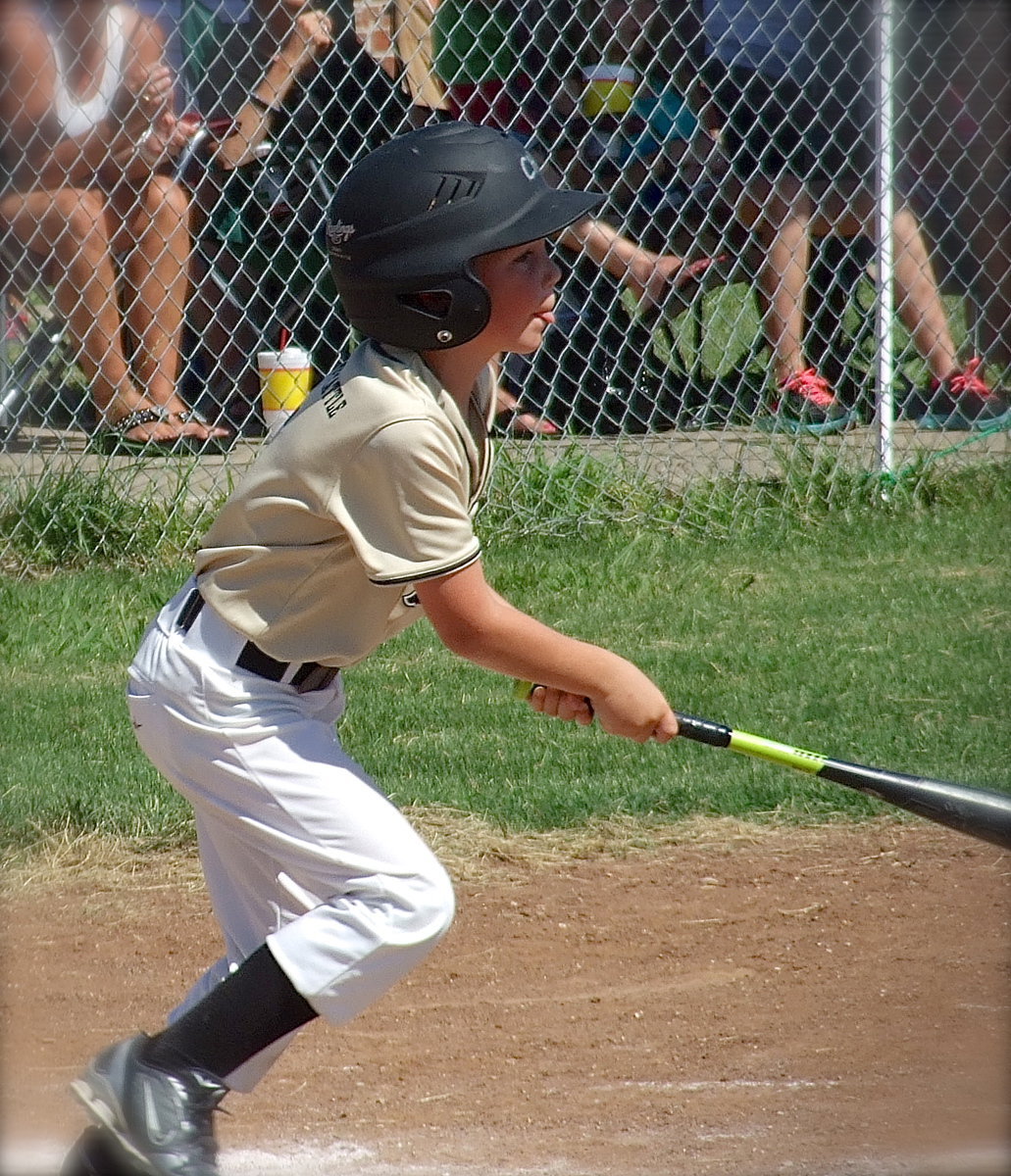 Image: Clayton Hellner(5) gets a lick and hurries to first base.