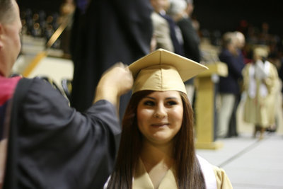 Image: Jasmin Flores gives the camera a big smile as Coach Ward moves her tassel over.