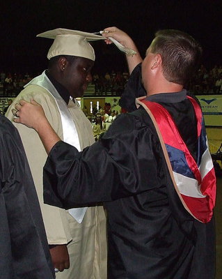 Image: Josh Ward adjusts the tassel for 2013 Italy High School graduate Adrian Reed after Reed received his diploma.