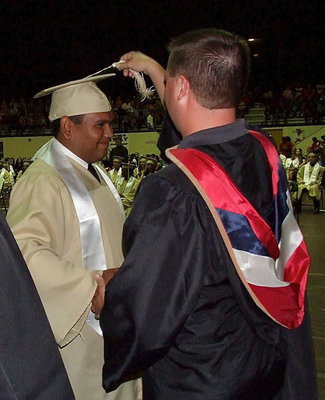 Image: Josh Ward adjusts the tassel for 2013 Italy High School graduate Jonathan Davila after Davila received his diploma.