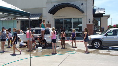 Image: Cheerleaders are working as a team to get the cars clean and cheerful looking.