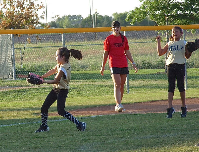 Image: Cheering on her pitcher is third baseman, Cadence Ellis, who is excited to see Emily Janek swoop in to catch a pop fly.