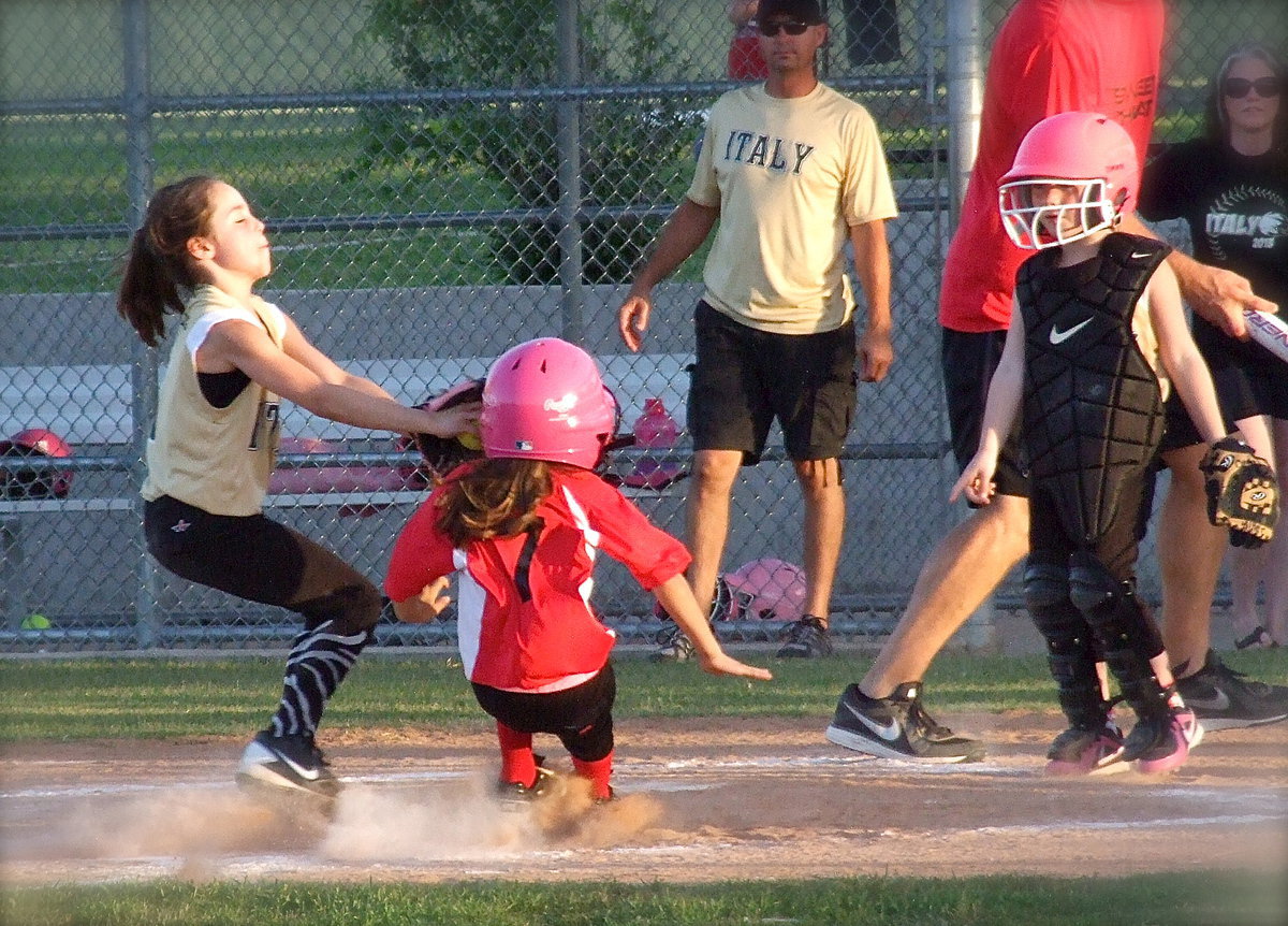 Image: With her eyes closed, and teammate Desi Miller looking on, Italy’s pitcher, Emily Janek, makes the face tag on a Waxahachie runner trying to sneak home. Despite the hustle by Janek, Waxahachie’s runner was sent back to third.