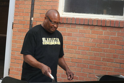 Image: Coach Larry Mayberry gets the BBQ pit ready for grilled hamburgers.