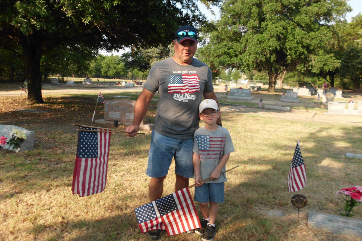 Image: J.D. Cate and son Austin help place flags in Smithwick Park.