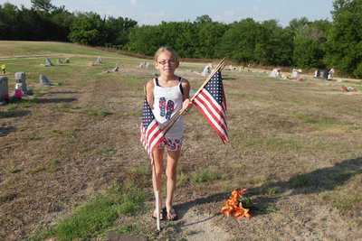 Image: Madie Chambers place flags on graves in Square Park.