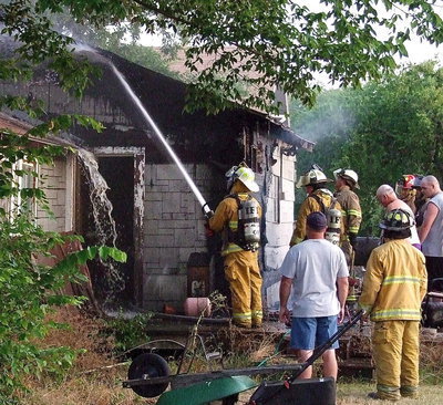 Image: Firefighters extinguish the blaze and then continue saturating the smoldering exterior.