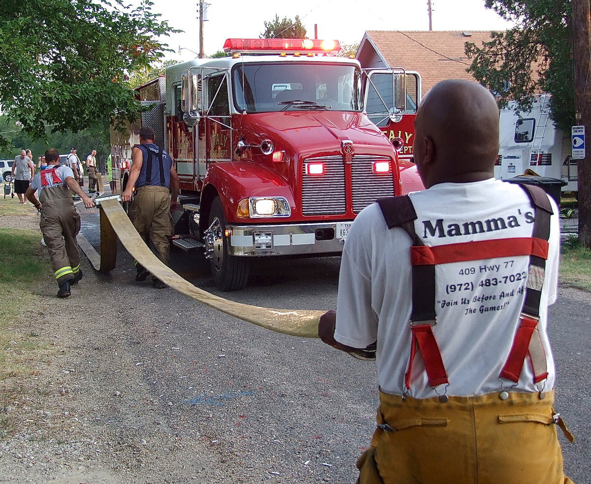 Image: Firefighters drain water from the engine hose before rolling the hose back up onto the truck.