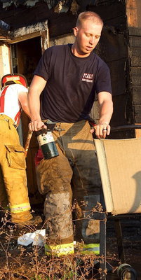 Image: Italy firefighter, Bryan Ward, removes flammable containers from the home.